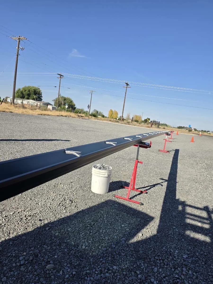 Dark seamless gutter run on roller stands, ready for installation