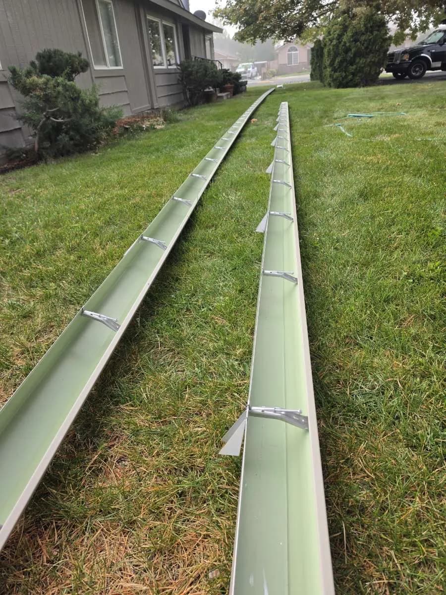 Two freshly formed seamless gutter runs on the lawn before residential gutter installation