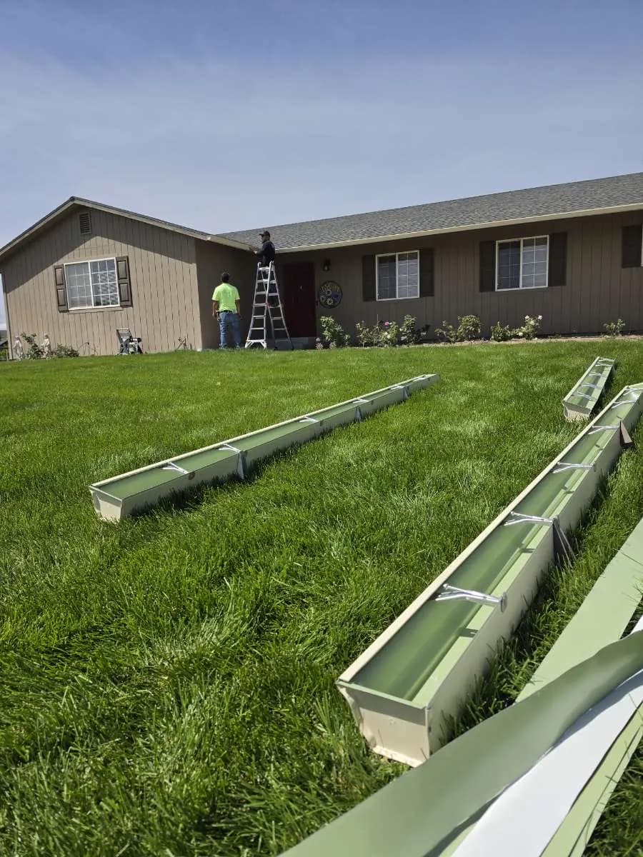 Ochoa & Sons crew on a ladder doing gutter repair along a residential roofline