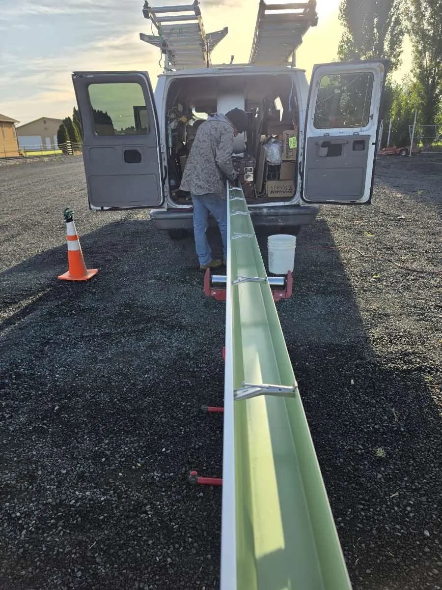 Ochoa & Sons crew forming seamless gutters on-site from the machine in their work van