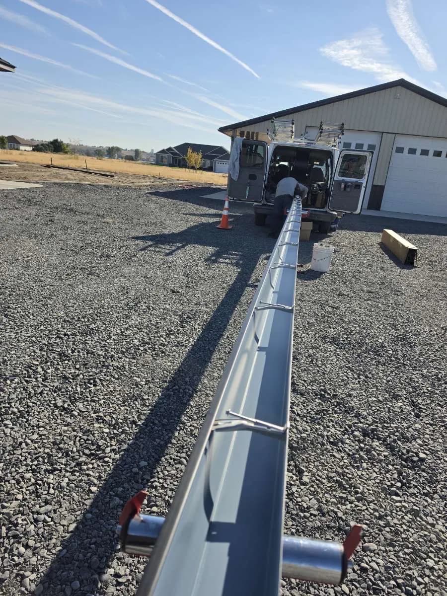 Seamless gutter run coming off the Ochoa & Sons forming machine during an on-site installation
